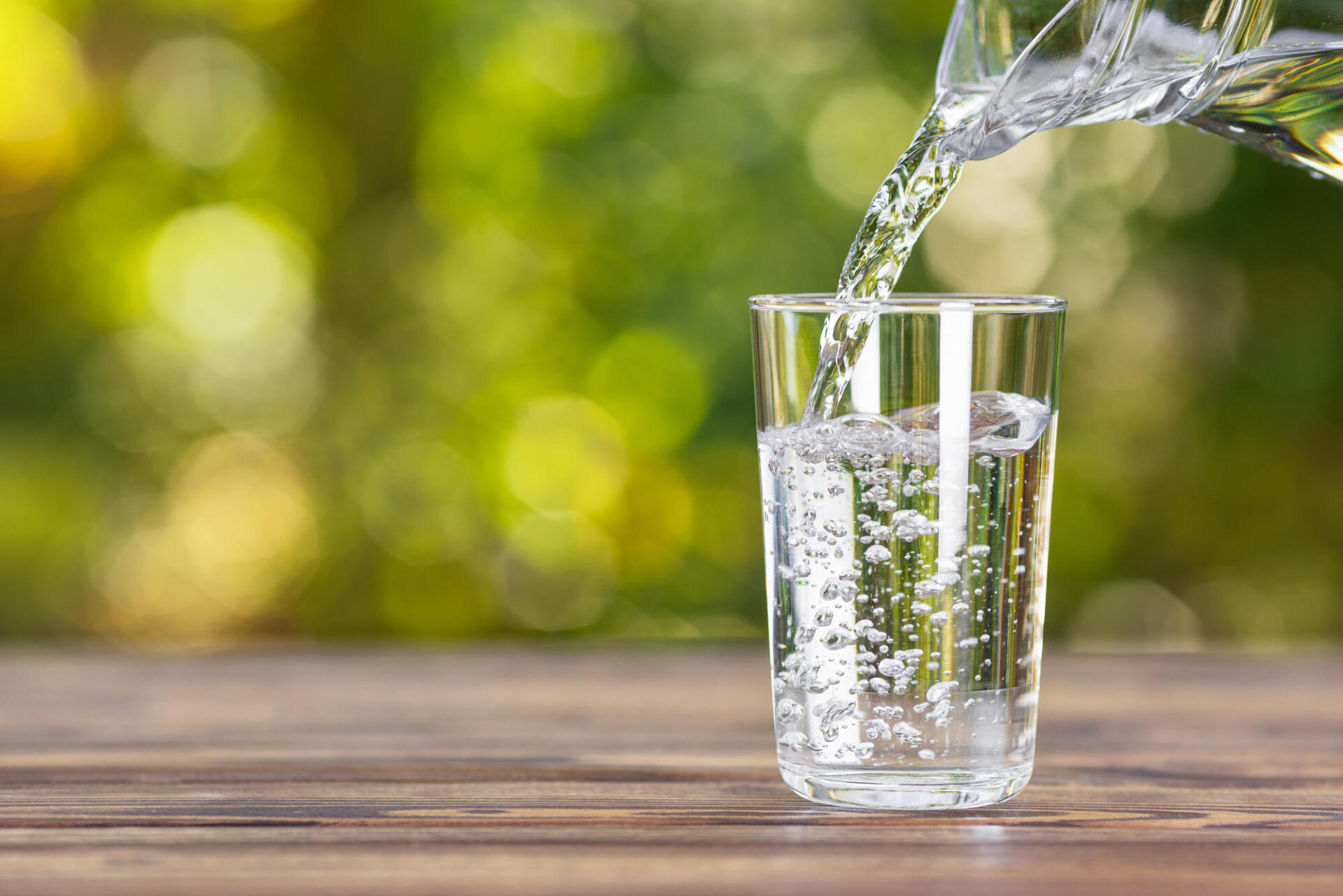 Bottle of water pouring into a clear glass